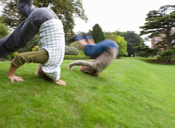 Two boys tumble down a sloping hill