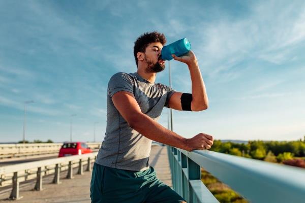 Man Taking a Break From His Run to Drink Some Water