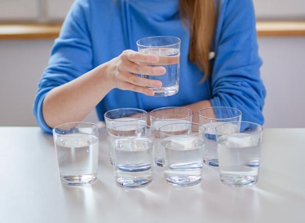 Woman sitting at a table with multiple glasses of water