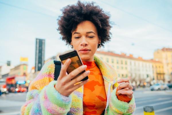 woman walking outside while checking her phone for notifications