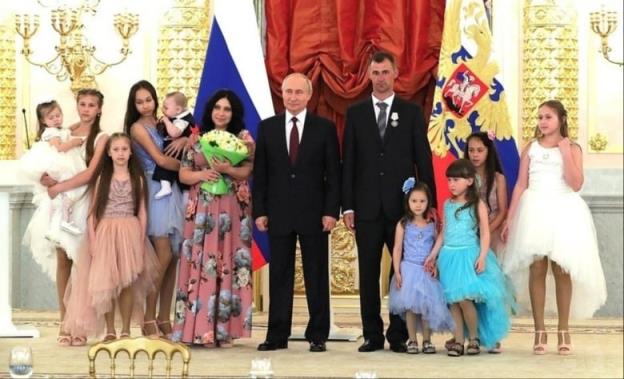 Lilia Syropyatova stands with her husband and their 9 children alo<em></em>ngside Russian President Vladimir Putin, who awarded them with the Russian ho<em></em>nour of 