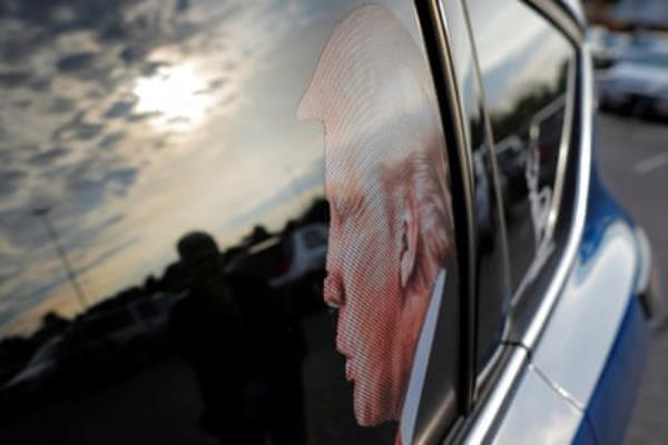 Trump in profile is seen on a car's back driver's side window.