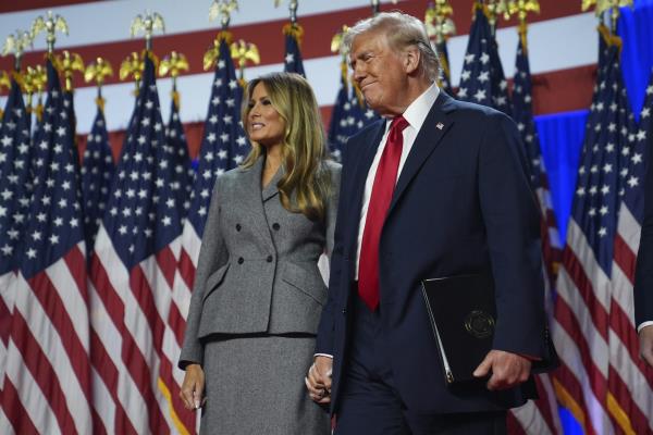 Do<em></em>nald and Melania Trump standing in front of US flags