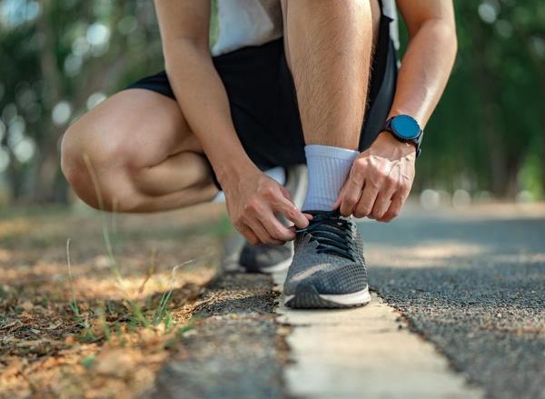 A man crouches down to tie his shoe laces