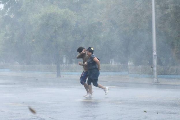 People are seen running on the street as Hurricane Rafael passes by Havana, Cuba.