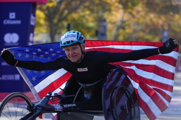 Susannah Scaroni crosses poses for photographs after winning the women's wheelchair division of the New York City Marathon, Sunday, Nov. 3, 2024, in New York.