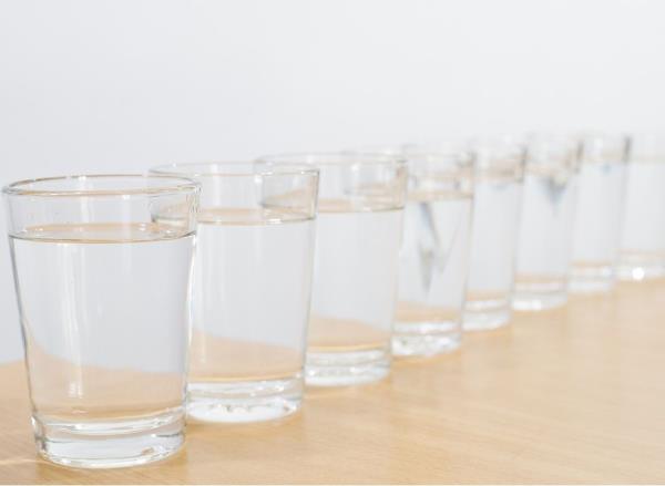 8 glasses of water lined up on a table