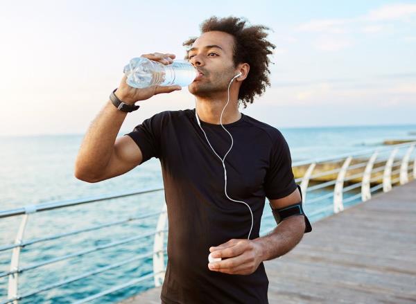 Man drinking water from a bottle during a run