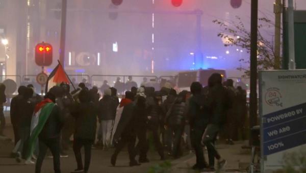 In this image taken from video, a group of pro-Palestinian protesters walk toward police line, with police vans driving in the background, near the soccer stadium in Amsterdam.