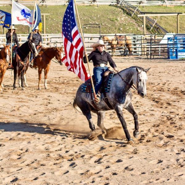 Samantha Dopp riding a horse carrying the American flag. 