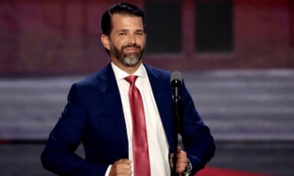 Do<em></em>nald Trump Jr smiles while talking in front of a microphone