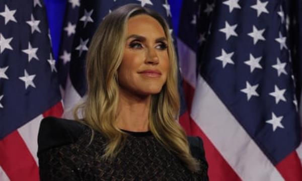 Lara Trump smiling while standing in front of American flags