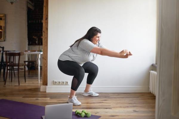 A woman performs a body weight squat.