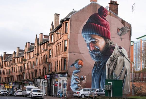 Glasgow's famous High Street mural of a modern-day version of St Mungo in a beanie, with a robin perched on his hand.