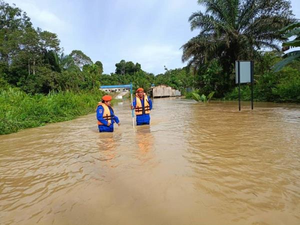 Handout photo shows Civil Defence Force perso<em></em>nnel mo<em></em>nitoring the rising water level at Jalan Raya, Sungai Laong Bakong, Beluru. — Picture courtesy of Civil Defence Force