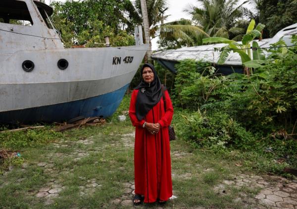 Saudah poses for pictures in front of coast guard ships that were carried a<em></em>bout five kilometres inland near her house in the city center of Banda Aceh December 21, 2024. — Reuters pic