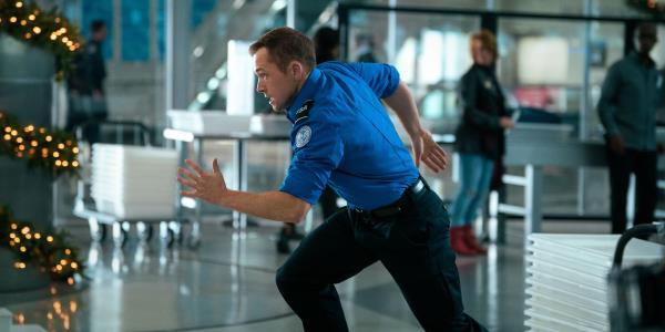 Taron Egerton in a TSA uniform sprinting through the airport in Carry-On