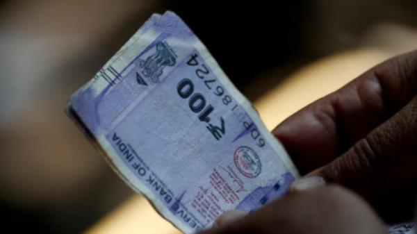 A customer holds hundred rupees Indian currency notes near a roadside currency exchange stall in New Delhi, India, May 24, 2024. Photo: REUTERS/Priyanshu Singh/File Photo