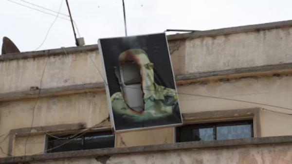 A burnt picture of President Bashar al-Assad hangs from a building, after rebels seized the capital and ousted the president, in Qamishli, Syria December 8, 2024. REUTERS/Orhan Qereman/File Photo